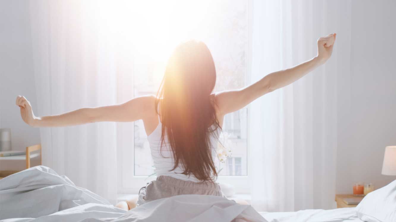 太陽の光を浴びて目覚める女性